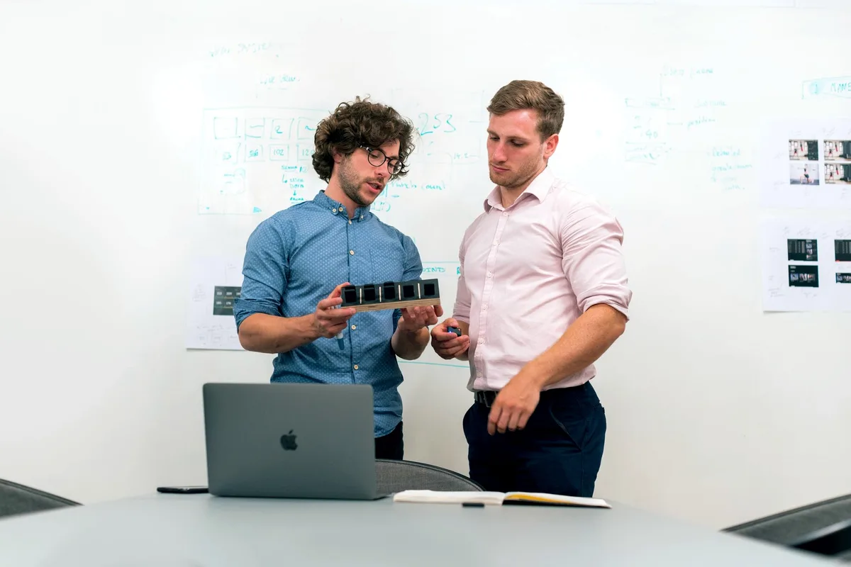 Ingénieurs travaillant ensemble sur une maquette devant le tableau blanc